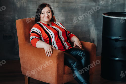 Preview: portrait of a business woman in a striped jacket sitting on a sofa in the interior