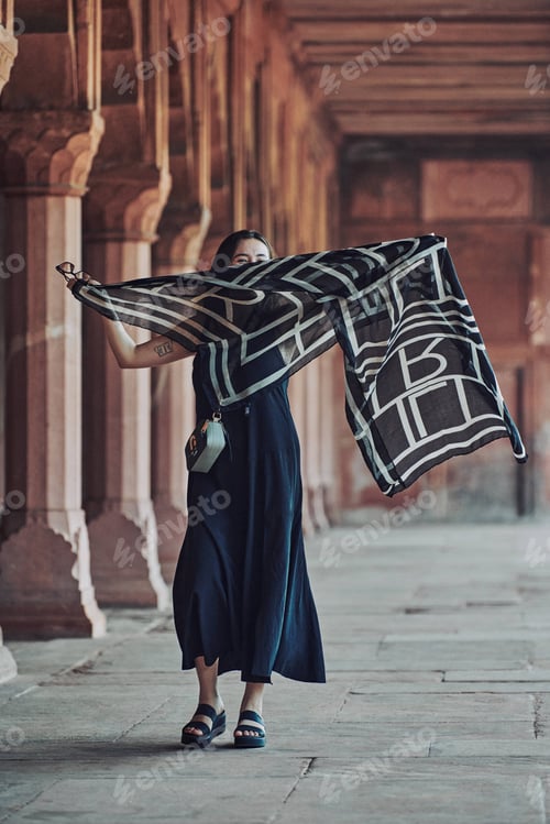 Preview: East asian woman in black dress dancing with translucent scarf among columns of ancient temple