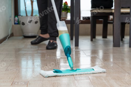 Preview: A man cleans the tiled floor in an apartment with a compact mop with a reservoir of detergent