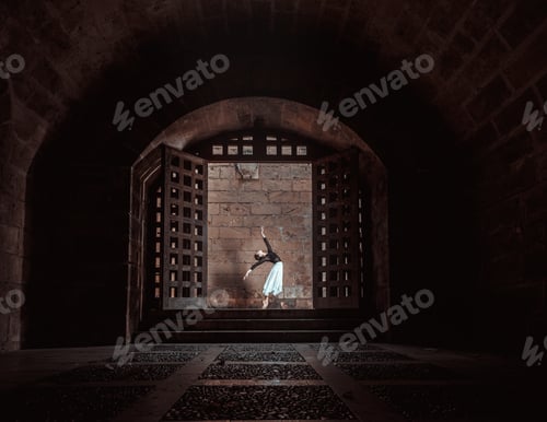 Preview: Young ballerina training between big wood doors near brick wall