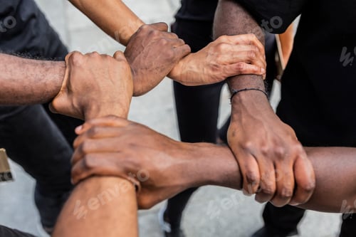 Preview: Faceless black friends joining hands on urban pavement