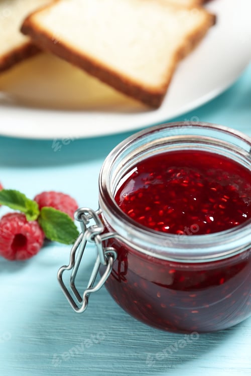Preview: Sweet raspberry jam and toasts for breakfast on turquoise wooden table, closeup