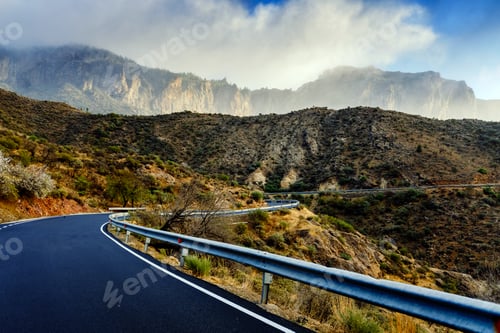 Preview: Winding road leads to high mountains with clouds to escape the routine and live adventures