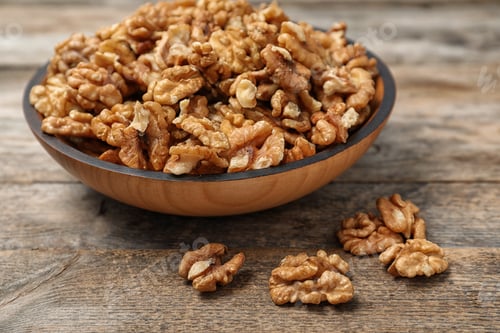Preview: Plate with tasty walnuts on wooden table