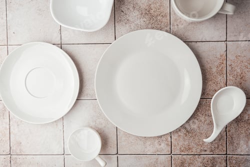 Preview: Assorted empty white plates and bowls on rustic tile background top view