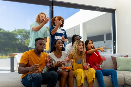 Preview: Group of focused diverse friends sitting on sofa, watching sport of tv