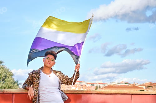 Preview: non-binary young asian person holding a non-binary flag with clouds in the background