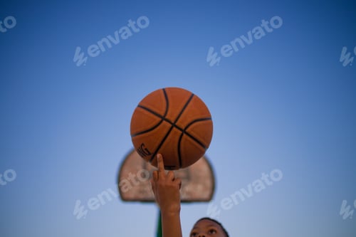 Preview: Low angle view of young boy seen spinning basketball on his finger