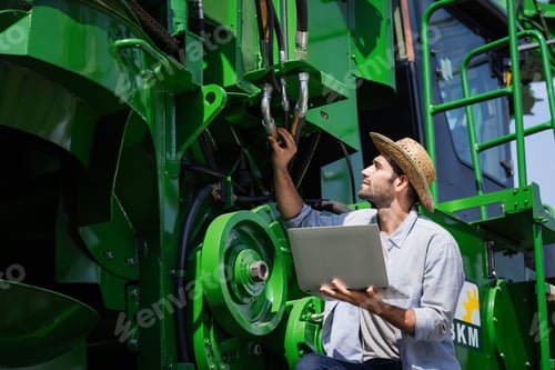 Preview: Technician Inspecting Farm Equipment with Laptop Outdoors