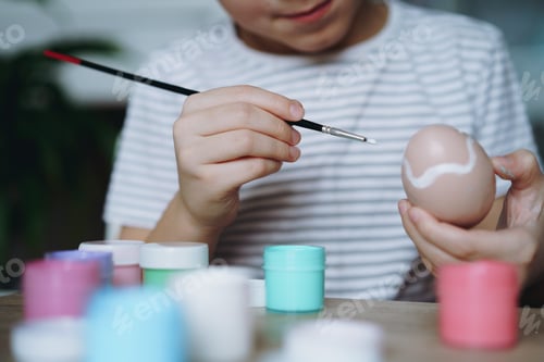 Preview: Close up view of boys hands colouring egg for Easter