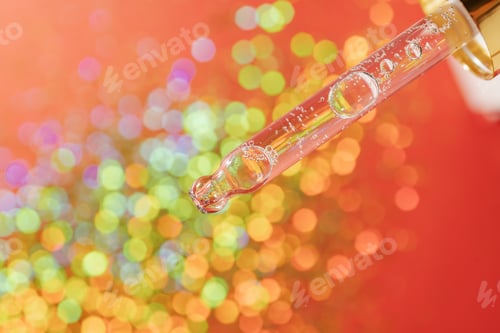 Preview: Pipette with serum on a red holiday background with bokeh.