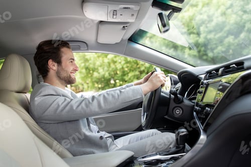 Preview: Stylish guy in suit driving in city with hand on steering wheel, empty space