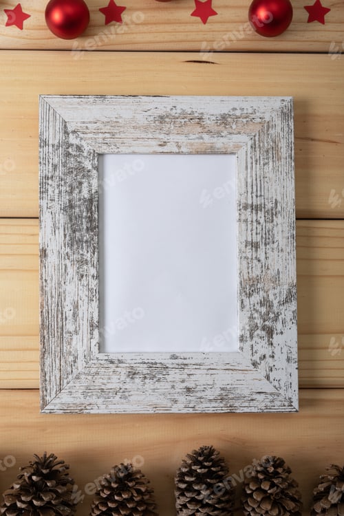 Preview: Composition of white card in frame with copy space, pine cones and baubles on wooden background