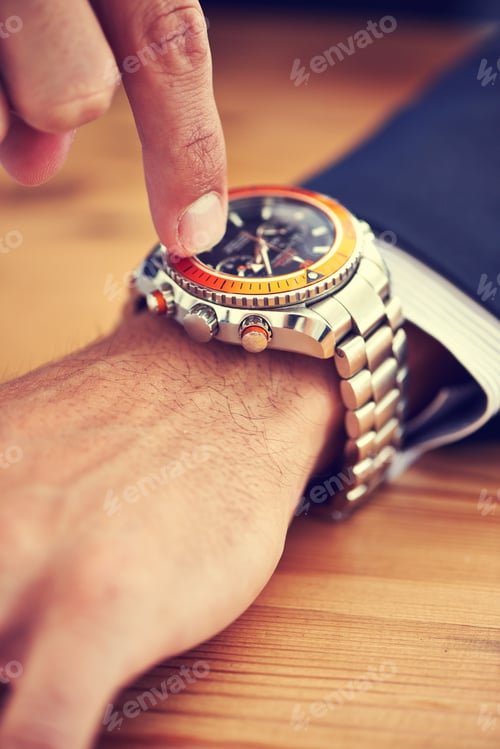 Preview: Man Adjusting Luxury Watch at Wooden Desk