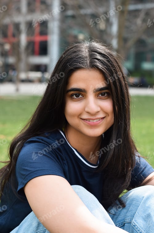 Preview: Closeup portrait of young girl with long dark hair looking straight at camera smiling