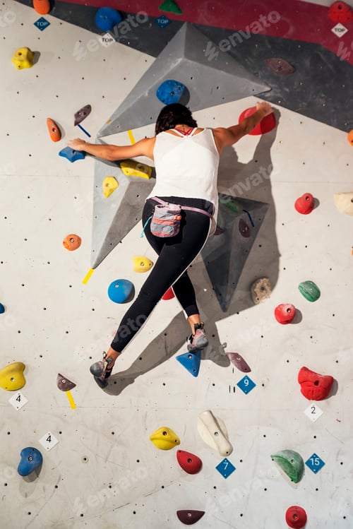 Preview: Woman practicing rock climbing on artificial wall indoors. Active lifestyle and bouldering concept.