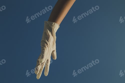 Preview: Closeup shot of a child's hand with white latex glove isolated on blue background