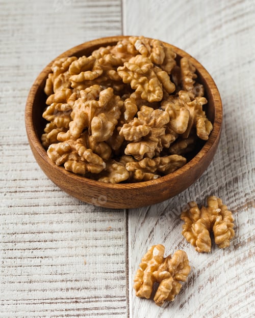 Preview: Peeled walnut in a wooden bowl on a white wooden background. Healthy eating, nuts.