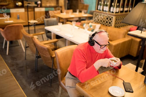 Preview: Positive senior man listening to music in headphones