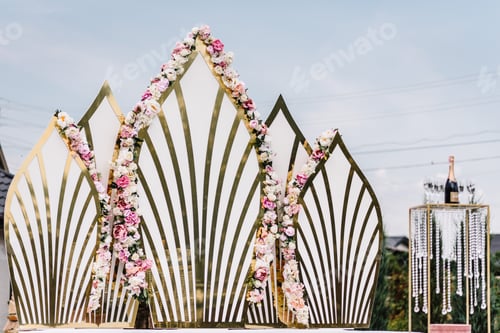 Preview: Arch for wedding ceremony a is decorated with flowers in the backyard. Gold decor. Original wedding