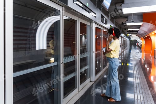 Preview: Young woman standing in front of subway at platform while listening music