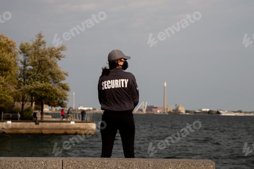 Preview: Closeup shot of a female security guard in uniform and mask watching over the harbor area