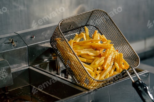 Preview: close-up in a professional kitchen the chef takes out french fries from the fryer