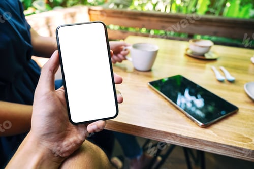 Preview: a man holding mobile phone with blank white screen with woman drinking coffee in cafe