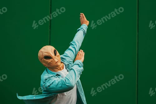 Preview: Alien doing dab posture and gesture against a green wall background. Extraterrestrial