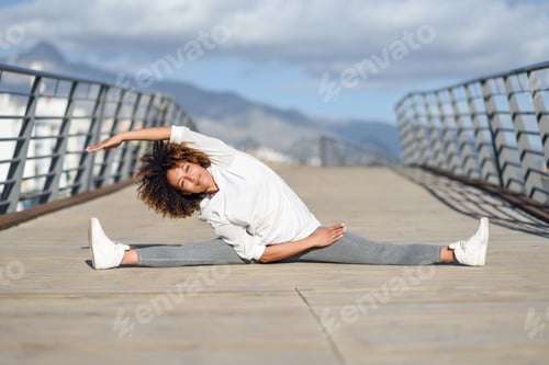Preview: Young black woman doing stretching after running outdoors