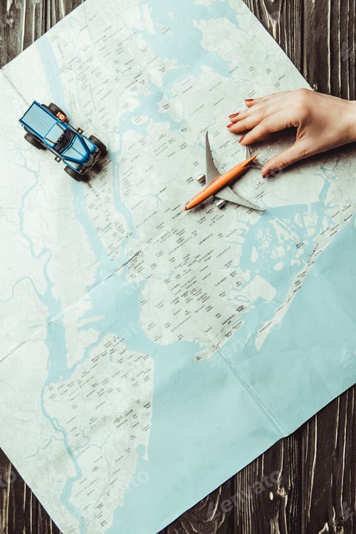 Preview: partial view of female hand, toys and map on wooden surface