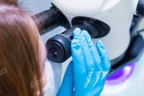 Preview: Professional female scientist doing experiment with electronic microscope in scientific laboratory