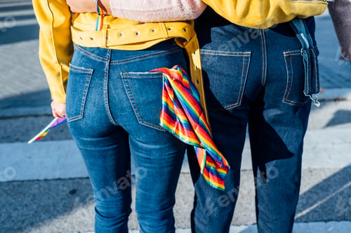 Preview: unrecognizable two women friends hanging out in the city waving LGBT