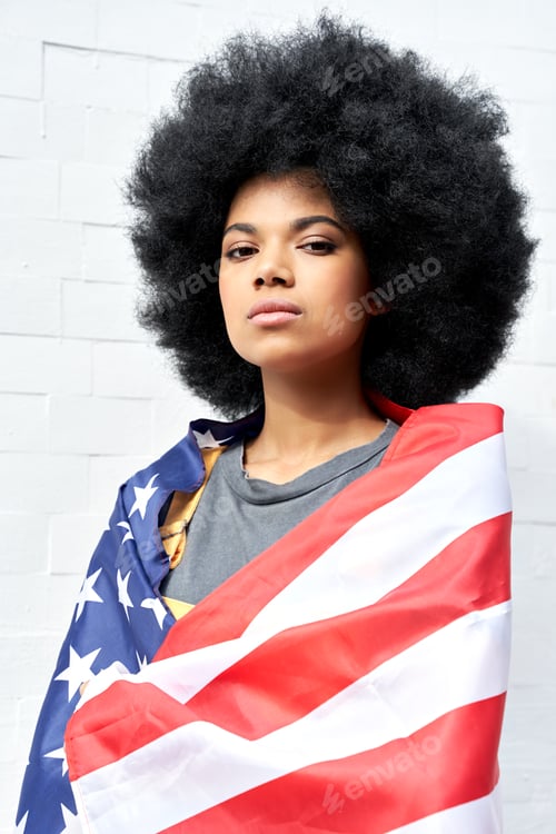 Preview: Proud African woman stand on white background wrapped in usa flag, portrait.