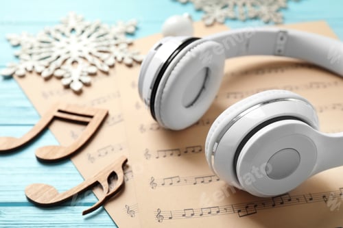 Preview: Christmas decorations, headphones and music sheets on blue wooden table, closeup