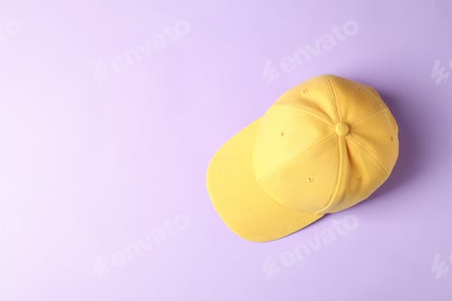Preview: Yellow baseball hat on violet background, top view. Space for text