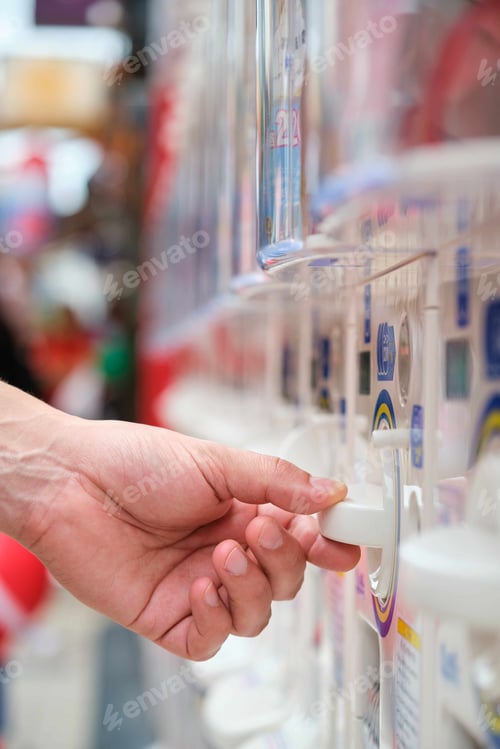 Preview: Hand buying a toy capsule at gashapon vending machine in Tokyo.