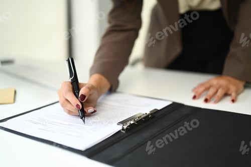 Preview: Closeup view of businesswoman signing contract, reviewing documents on office desk