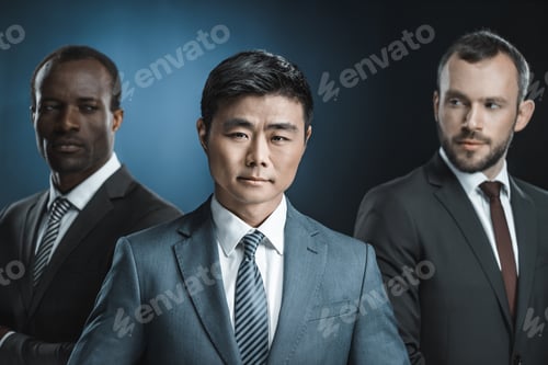 Preview: selective focus of multicultural group of businessmen in suits looking at asian colleague isolated