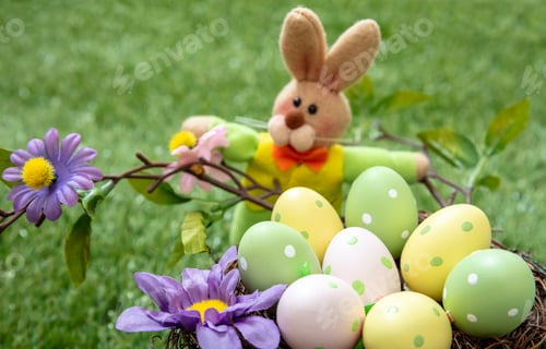 Preview: Happy Easter. Pastel colored eggs in a nest on green grass, close up view
