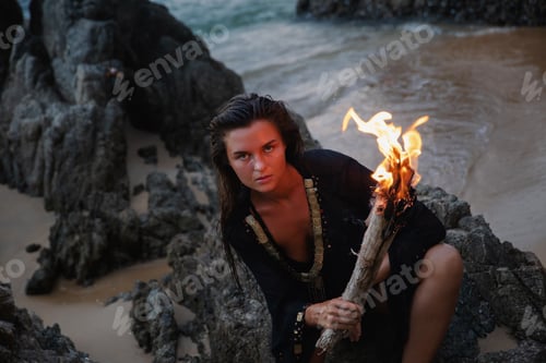 Preview: Mysterious woman on the beach at dusk and holding a flaming torch