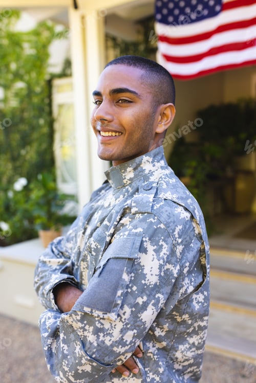 Preview: Happy biracial male american soldier wearing military uniform standing outside the house