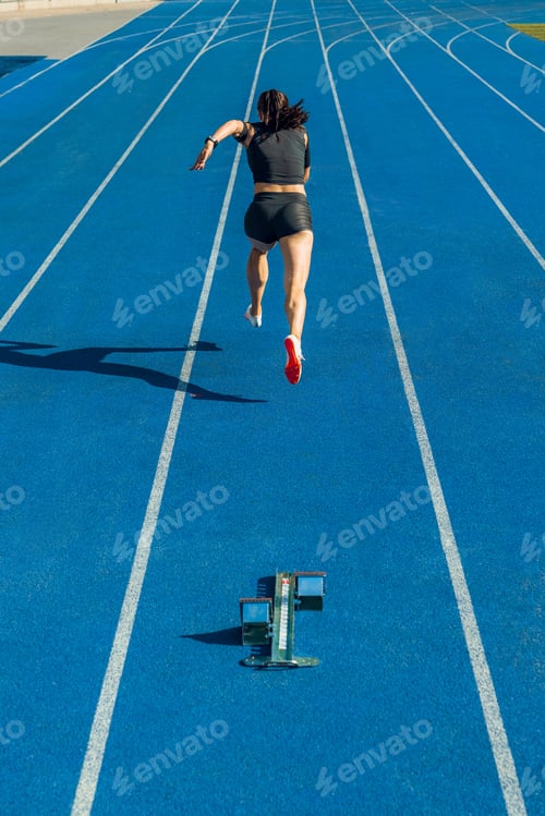 Preview: Rear view of female athlete running on track at sports stadium