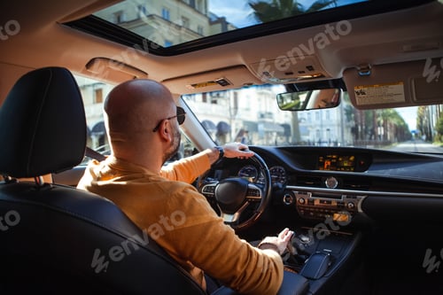 Preview: bald bearded middle-aged man drives a car