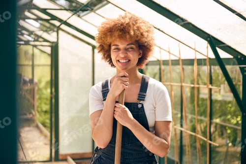 Preview: Portrait Of Smiling Woman With Broom Working In Greenhouse At Home