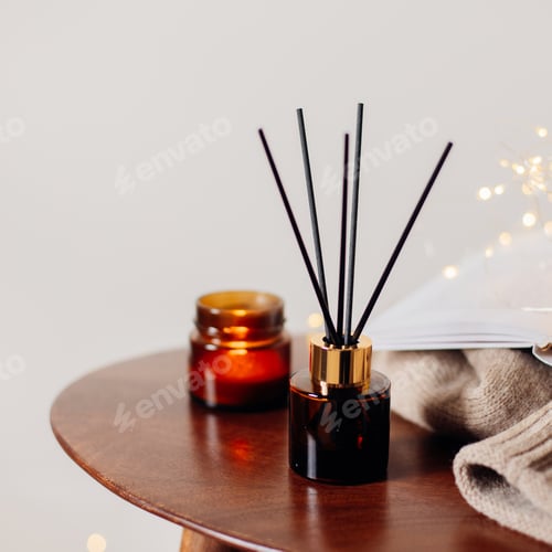 Preview: Home aroma fragrance diffuser and burning candles on wooden table in the bedroom.