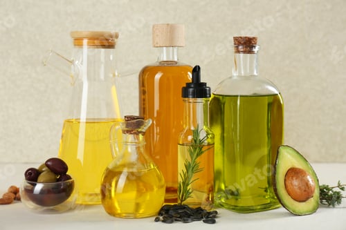 Preview: Vegetable fats. Different cooking oils in glass bottles and ingredients on white table