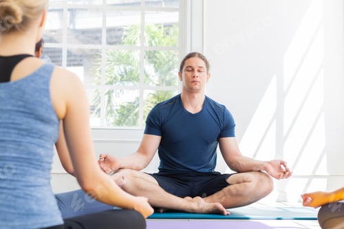 Preview: Group of sporty people practice meditation with yoga instructor in fitness class