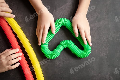 Preview: anti stress sensory pop tube toys in a kids hands. kids hands plays with poptube toy on black table