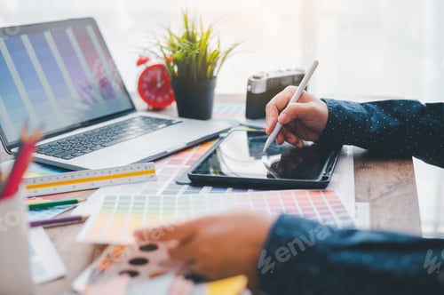 Preview: Graphic designer architects who work with laptops and color comparison tables for design work.